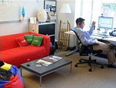 Trabalhadores discansando em uma sala com computador e um sofá